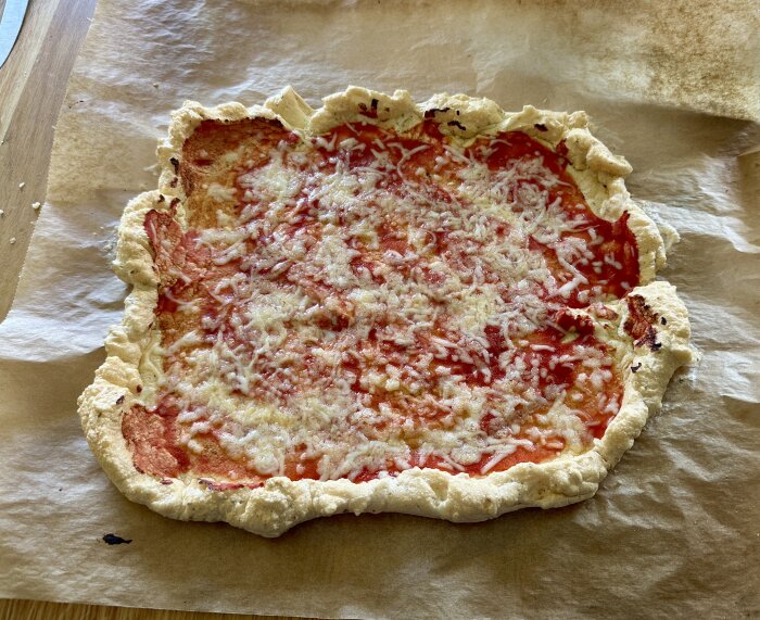 Pizza med ost och tomatsås på botten gjord av vispad äggvita och majsstärkelse, bakad på bakplåtspapper.