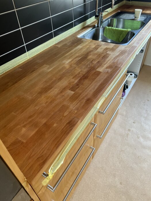 Slipad och inoljad köksbänk av trä med ho och blandare.