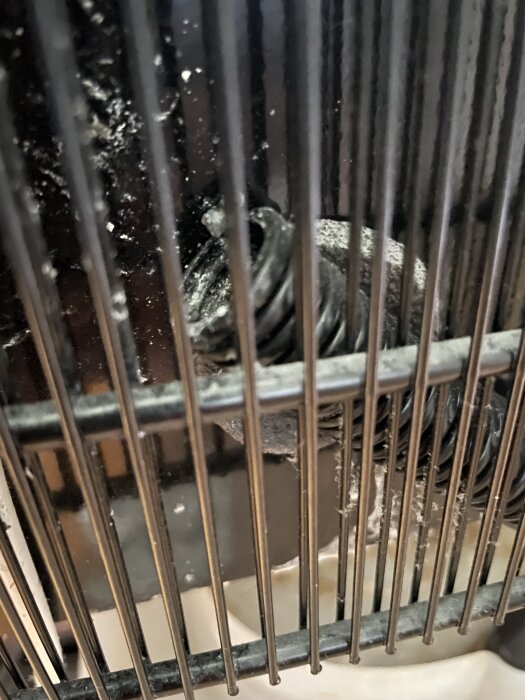 Vattenrör och droppskål bakom kylskåpsgaller, potentiell källa till vattenläckage, i en Huskvarna kyl från 2011.