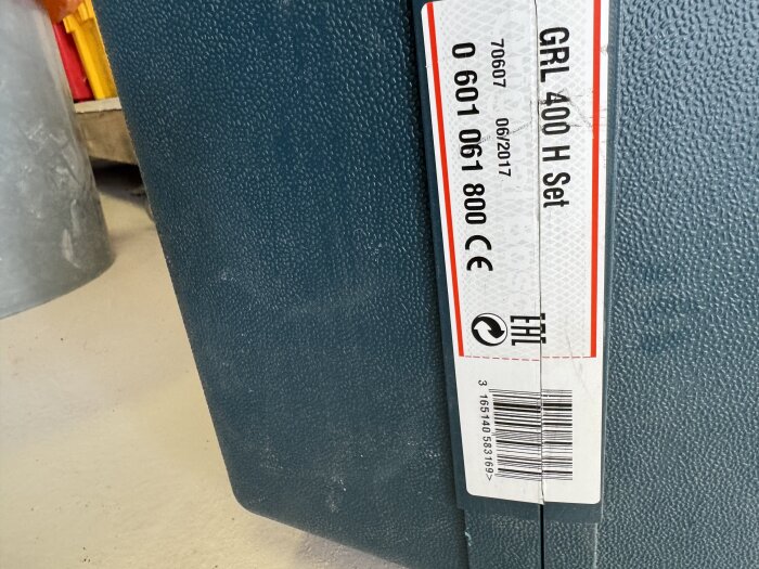 GRL 400 H Set i en skyddslåda, använd med stativ och mätpinne för byggprojekt. Står på golv, etikett med produktinformation synlig.