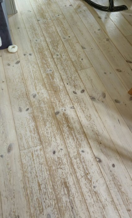 Vitbetsat furugolv i kök med synligt slitage och träets ådring tydlig efter åtta års användning.