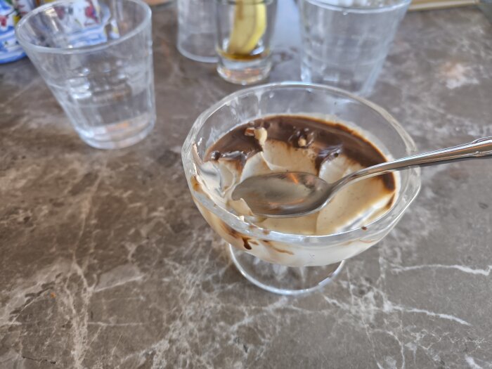 Skål med delvis uppäten pannacotta och en sked, placerad på ett bord.