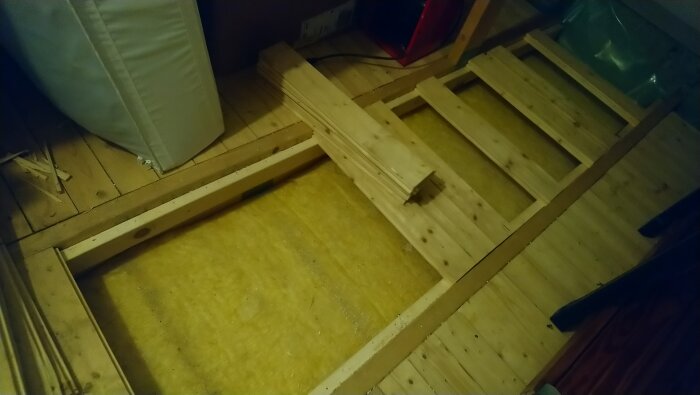 Öppnat golv på garagevind med synlig isolering och golvbjälkar, förberett för kabeldragning till installation av laddbox och solceller.