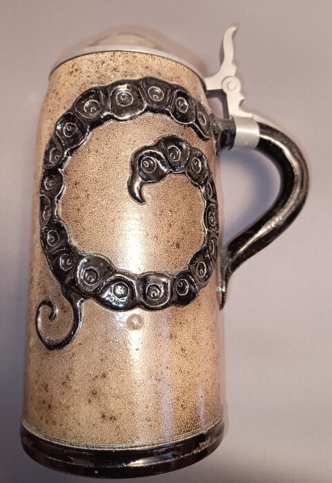 Ölkrus med tennlock från 1920- eller 30-talet med ormmönster, stämplat DBWBG för tysk formgivning, möjligen från en historisk ölstuga.