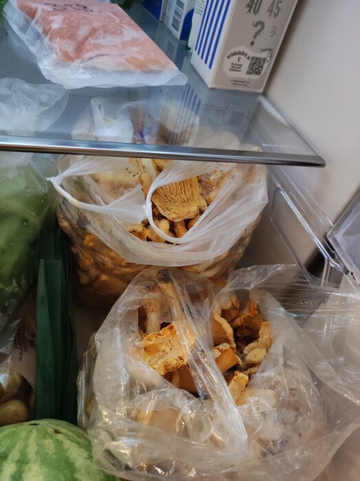 Plastpåsar fyllda med kantareller i ett kylskåp.