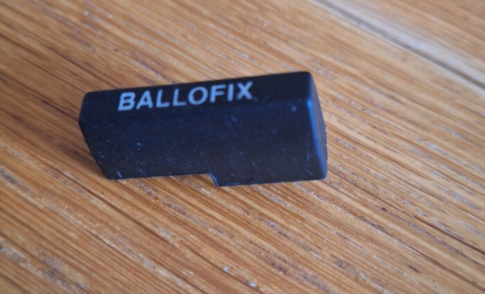Svart Ballofix-handtag av plast på en träyta.