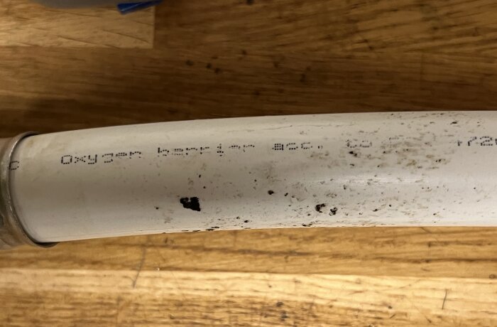 Vit rörledning med delvis avskavd text som inkluderar "Oxygen barrier". Rörledningen är en del av en värmepumpsinstallation.