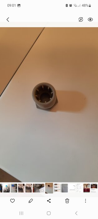 En vit plastkoppling på ett bord, som inte passar till vattenanslutningen för en tvättmaskin.