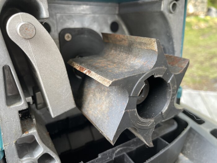 Närbild på knivar i en maskin, troligtvis del av en hyvelmaskin, med metalliska och rostiga detaljer.