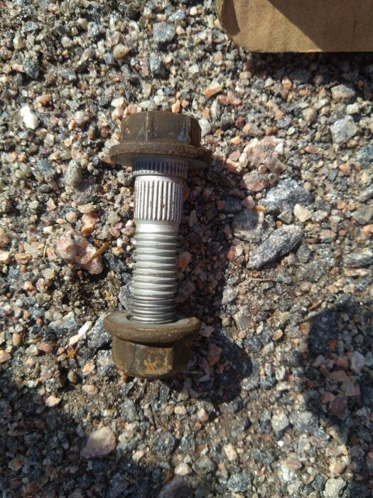 Rostig bult och mutter på grus, använd i stötdämparbenet.