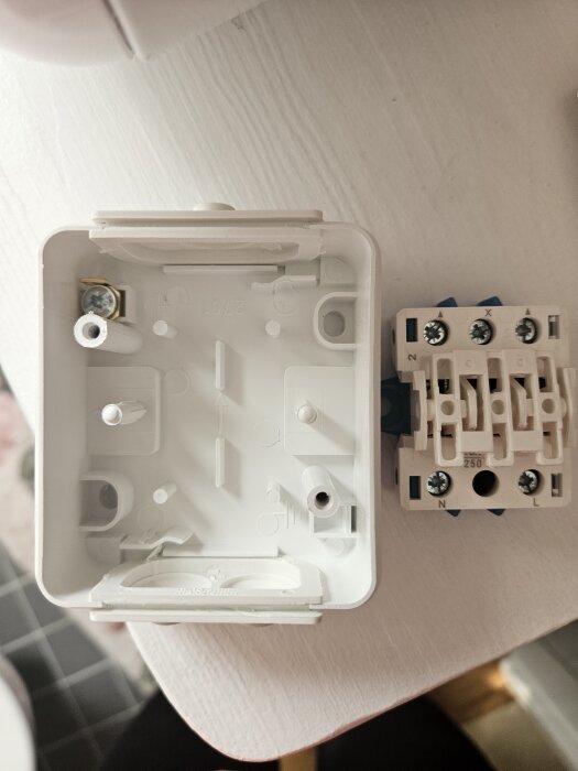 En öppen elbox och en strömbrytarpanel på ett bord, förberett för installation på en torktumlare.