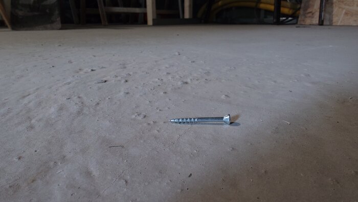 Närbild av knottrigt golv med en metallskruv (4.2*41) som referens, visar ojämn yta.