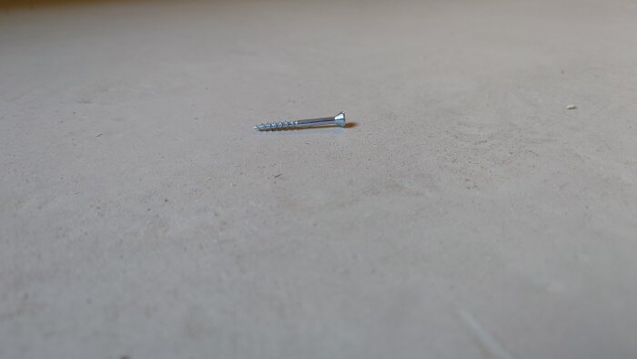 En skruv på ett småknottrigt golv används som referens för ytans textur.