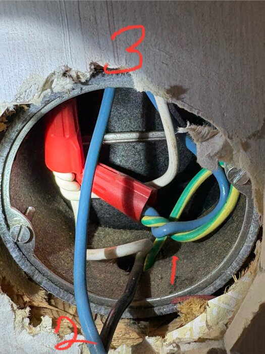 Elcentral med öppet kopplingsdoslock visar vita, svarta, blå och grön/gula kablar samt röda kontaktdon, siffror 1, 2, 3 markerade i rött.