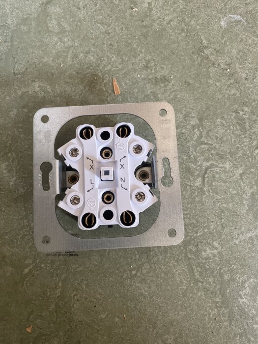 Gammalt eluttag med flera uttag och markeringar för sladdanslutning, sett ovanifrån på ett grått underlag.