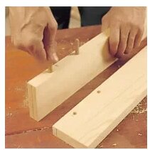 Träplugg placeras i borrade hål på trästycken för att sammanfoga dem.