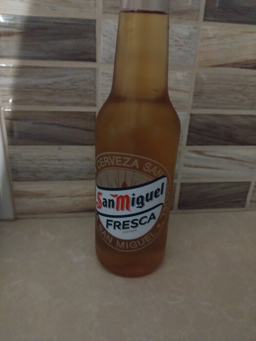 Flaska med San Miguel Fresca öl på ett bord framför kaklad vägg.