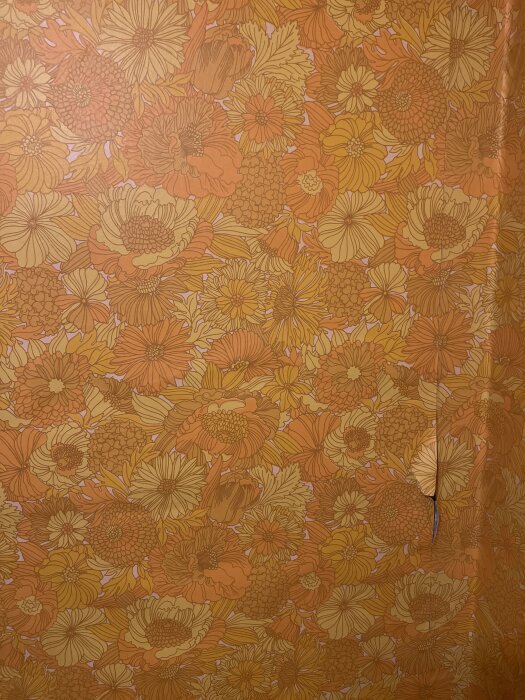 Blommig tapet i orange och gula nyanser med ett synligt veck.