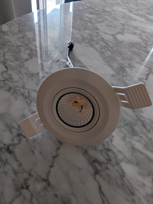 Rund spotlight på marmorbord med en ansluten elkabel.