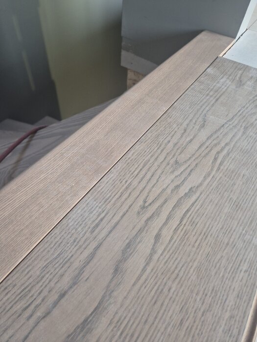 Trätrappa med intilliggande golv som diskuterar fogfri installation utan list, matchande höjder.