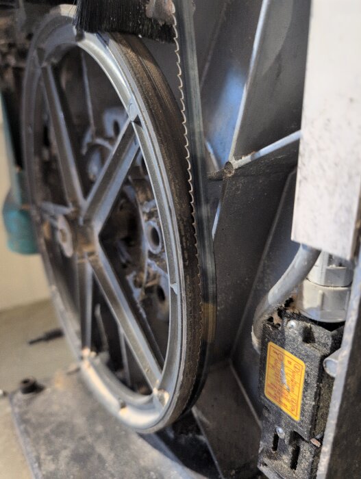 Närbild av det övre hjulet på en Inca bandsåg, där gummit sticker ut 1-2 mm utanför hjulet, med sågbladets tänder synliga.