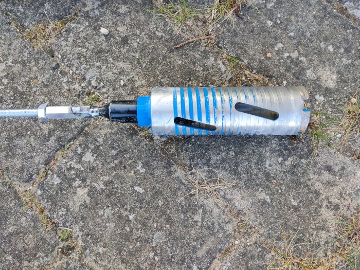 Hemmagjord borradapter med M10-gängstång och hålsåg på marken.