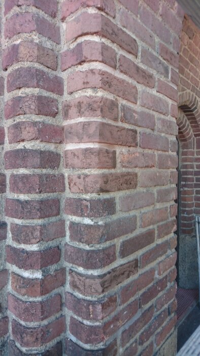 Murad tegelvägg med puts, delvis färgad med egenblandad kalkfärg, visar ett hörn av muren på Stockholm stadion.