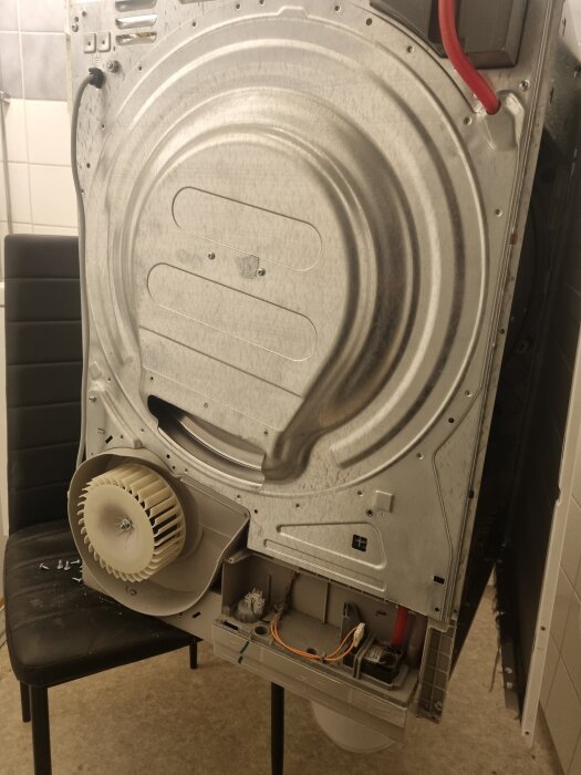 Baksidan av en äldre AEG torktumlare, synlig fläkt och öppnad panel med kablar.