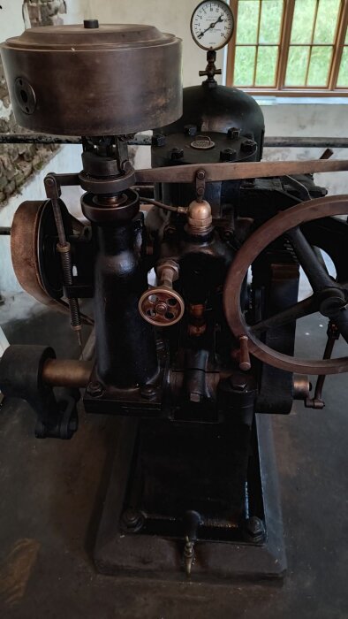 Gammal maskin från kraftverk i mellannorrland, byggd under första världskriget, med stora kugghjul och tryckmätare.