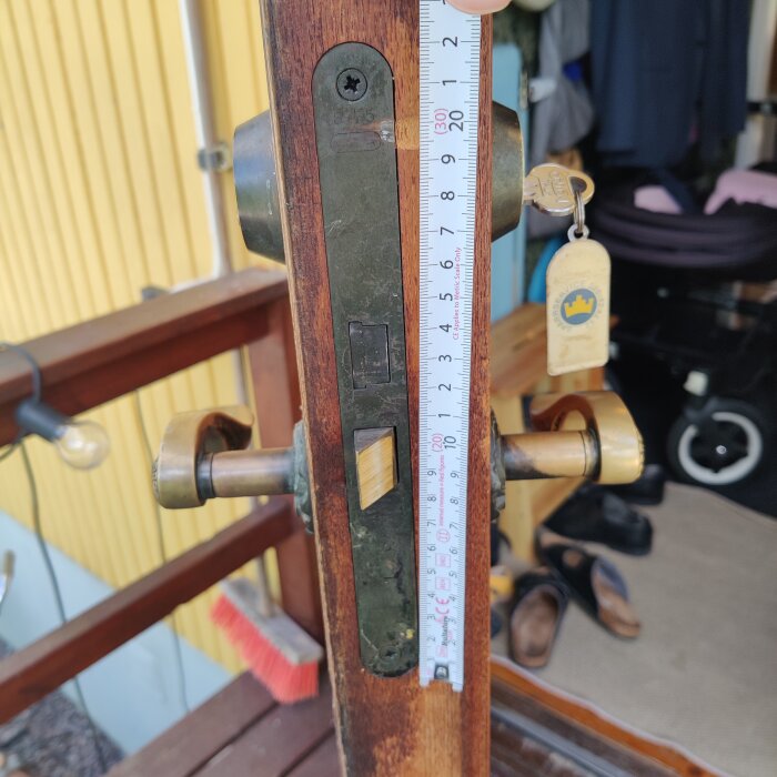 En gammal dörr med lås och metallregel, en mätskala visar längden.