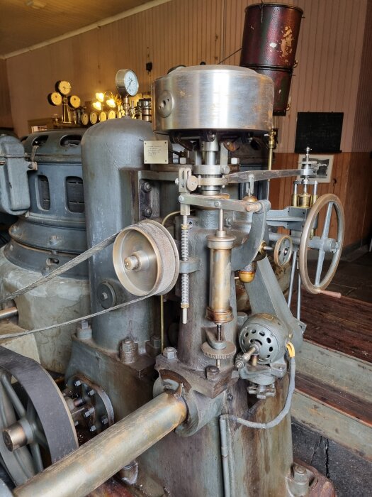 Gammal kraftstationsutrustning med detaljerad mekanik och mätare, elegant armatur syns i bakgrunden.