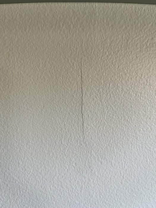 Vit köksvägg med liten färgkant orsakad av ojämnt målad våtrumsfärg, synlig i mitten av bilden.