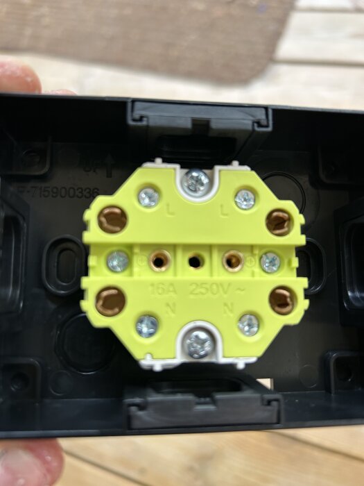 Gul eluttaginsats för 16A, 250V med märkningar "L" och "N" synliga, monterad i ett svart hölje.