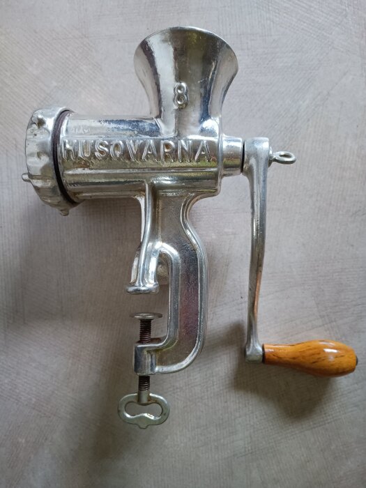 Handvevad köttkvarn i förtennat gjutjärn från Husqvarna, använd för att mala kött och stoppa korv, med trähandtag och bordsklämma.