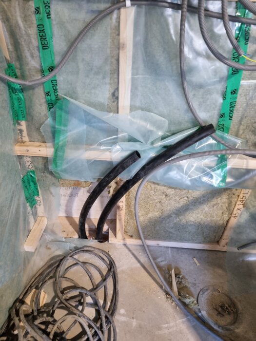 Rörinstallation för bergvärme med synliga kablar vid en isolerad vägg.