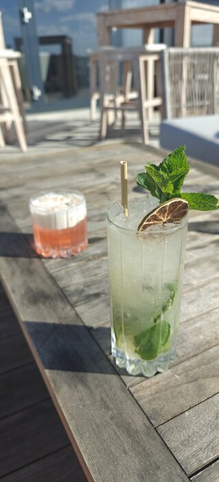 Två drinkar på ett träbord utomhus vid Tylösand strand, en med mynta och lime och den andra med skum.