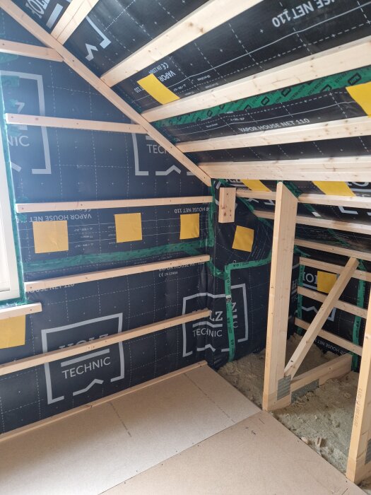 Tak och vägg i ett renoveringsprojekt med träreglar, teknisk duk och tejp. Isolering har tagits bort från långsidorna.