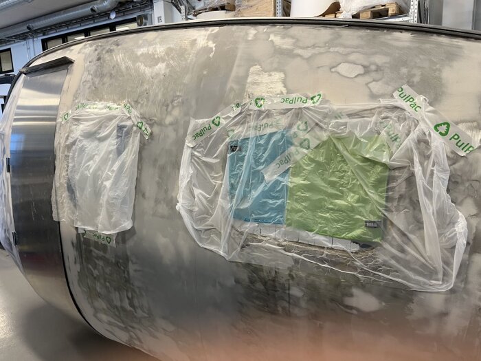 Bastuvagn med tejpade fönster täckta av plast, del av renoveringsprojekt där skyddsfilm spruckit och orsakat problem med fönstren.