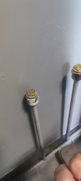 Två rör med metallförslutningar på grå vägg, del av renoveringsprojekt i tvättstuga.