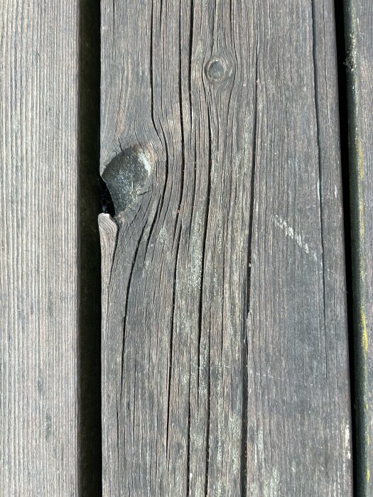 Gammalt altangolv av trä med synliga sprickor och en flagnad yta, möjligtvis täckt med färg eller lasyr.