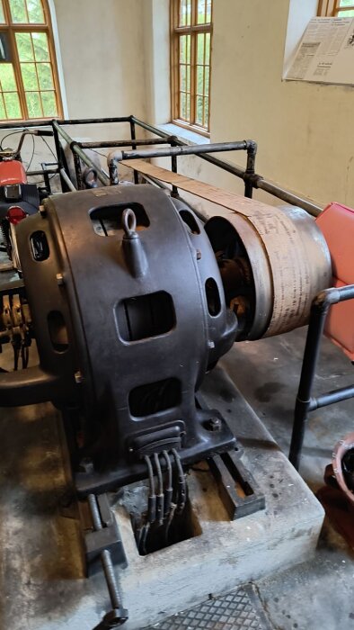 Generator och mekaniska delar i Franshammars kraftstation, med fönster i bakgrunden och metallkonstruktioner runtomkring.