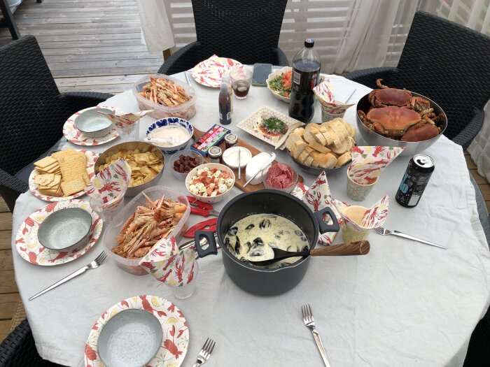 Bord dukat med krabba, musslor, räkor, bröd, sallad, dryck och tilltugg för en måltid.
