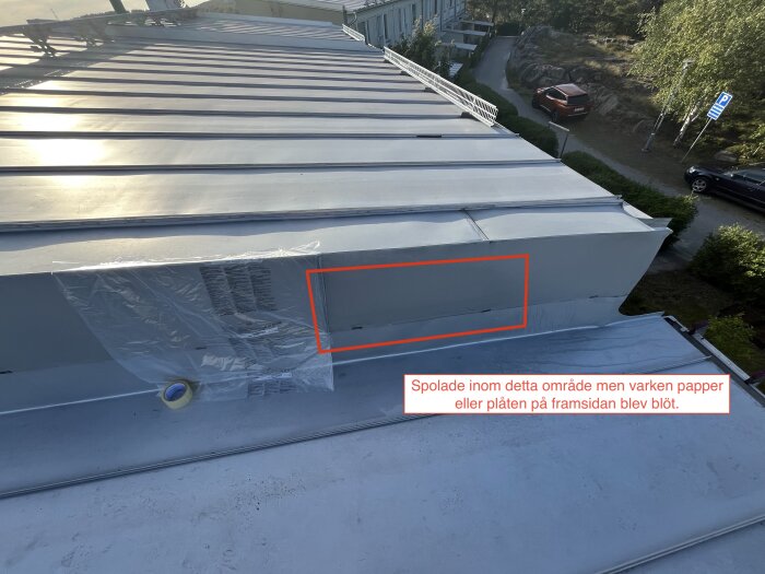 Tak med tejpade plåtsektioner och markerad sektion. Plast och tejp syns över en fog för att testa vatteninträngning.