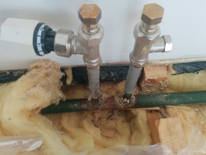 Två metallrör anslutna till ett grönt rör i isoleringsmaterial, del av ett enrörssystem för radiatorer.