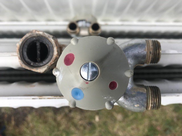 Ett rörsystem med en delad sektion och en koppling ovanpå, förmodligen en äldre lösning. Rören är ihopkopplade med en plastkontrollventil.