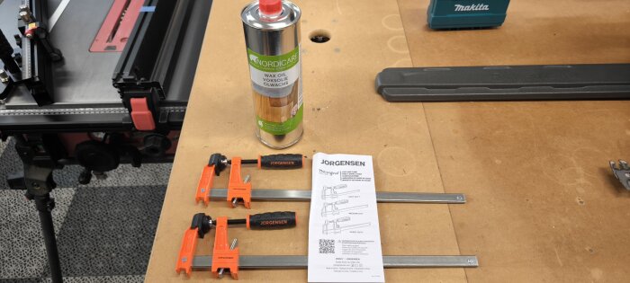 Verktygsbänk med tvingar från Jorgensen, bruksanvisning, burk med Nordicare vaxolja, och delar av en såg- eller arbetsbänk.