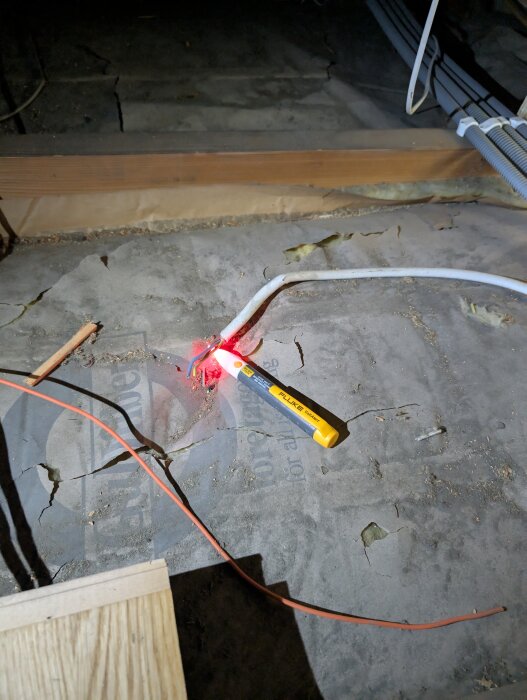 Multimeter som mäter spänning på vindens kabel, med ljusalarm som indikerar aktiv 400 V ledning. Kablage är prydligt klamrat längs med golvet.