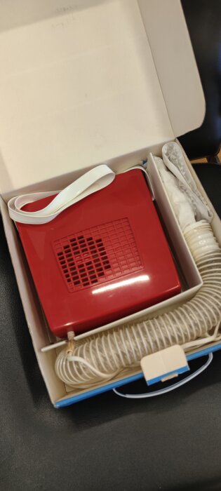 Röd oanvänd enhet med fläkt och sladd i vit kartong.