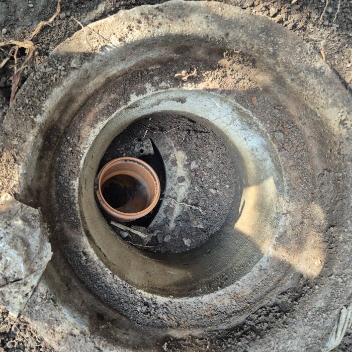 Plaströr nedlagt i en brunn omgiven av jord och rötter.