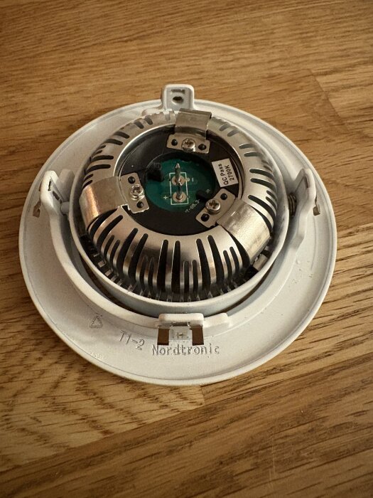 Spotlight med namnet Nordtronic, inklusive del av den elektriska kretsen, ligger på ett träbord.